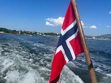 Ferry leaving Bergen harbor with dramatic fjord and mountainous backdrop